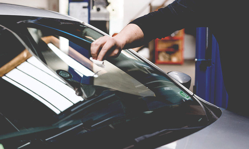 Auto Glass Technician cleans glass after new windshield installation